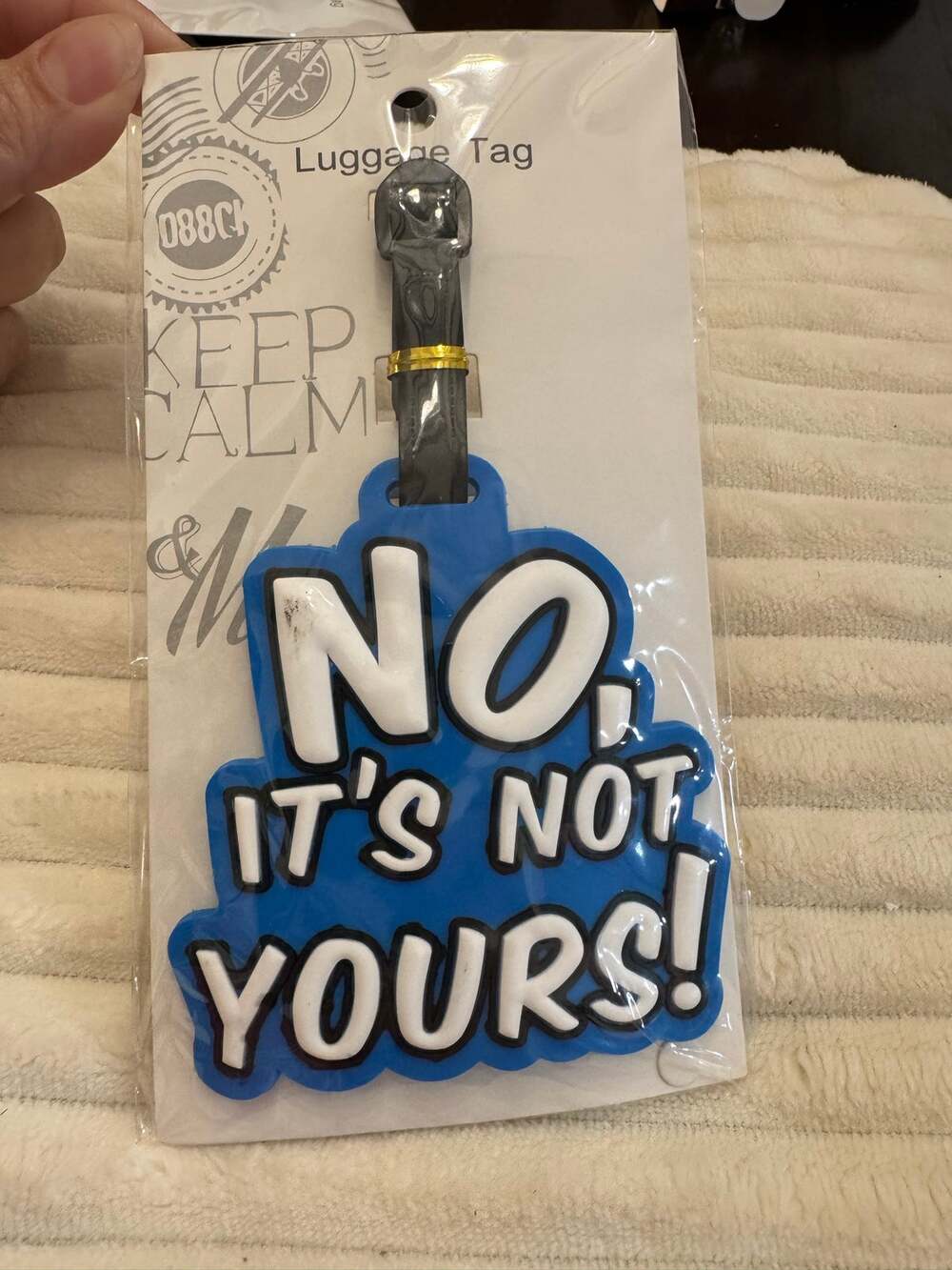 Rubber luggage tag  blue background and white text reading 'NO, IT'S NOT YOURS!